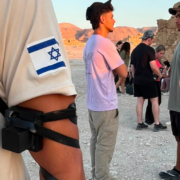 Tourists and guide at Masada with Israeli flag patch visible.