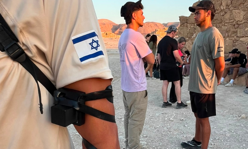 Tourists and guide at Masada with Israeli flag patch visible.